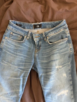 Blå jeans från LTB med slitningar - Snygga blå jeans från LTB med slitna detaljer framtill. Jeansen ära storlek 27/34. Lågmidjade och flared. 