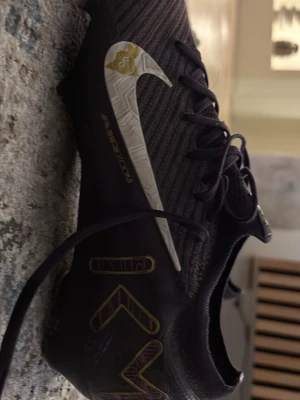 Nike Mercurial fotbollsskor mörklila Elite köpte för 2600 - Pris kan diskuteras. Säljer ett par Nike Mercurial fotbollsskor i mörklila med guld- och vita detaljer. Skorna har snörning och är tillverkade i syntetmaterial för bästa grepp och känsla på planen. Perfekta för dig som vill sticka ut med stil på fotbollsplanen.