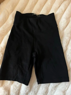 Svarta cykelshorts leggings - Svarta cykelshorts leggings med hög midja och stretchigt material. Perfekta för en sportig look eller att styla med oversized t-shirt. Mjuka och bekväma med tight passform som följer kroppen.
