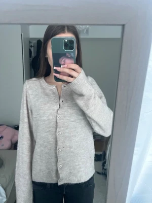 Rosa,Beige kofta med knappar - Mysig beige kofta med rund halsringning och knäppning framtill. Långärmad och i mjukt stickat material, perfekt för lager-på-lager. Enkel och stilren design som passar till det mesta.