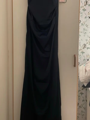 Mörkblå satinklänning - Jättevacker mörkblå satinklänning från Nelly. Klänningen är i ett extremt mjukt och skönt material och har en väldigt fin öppen rygg!! Den är aldrig använd och kostar 899 kr på hemsidan💙