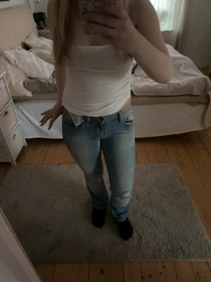 Ljusblå jeans med hål i och köpta från en secondhandbutik  - Säljer ett par ljusblåa jeans från en secondhandbutik. De är ganska raka i bena men ändå lite utsvängda längst ner. De står inte storlek men skulle gissa på XS