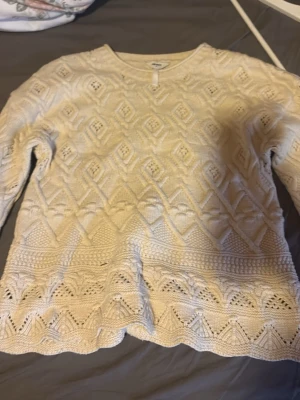 Vit mönstrad stickad tröja - Snygg vit stickad tröja med unikt mönster och vågig kant nertill. Tröjan har lång ärm och rund halsringning, perfekt för lager-på-lager och en chill look. Materialet känns mjukt och bekvämt, och mönstret ger en extra touch till outfiten.