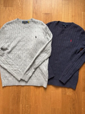 Kabelstickade tröjor från Polo Ralph Lauren - Två kabelstickade tröjor från Polo Ralph Lauren, en i ljusgrått och en i mörkblått. Bundel 2-pack. Äkta. Strl S. Riktigt fint skick. Pris kan diskuteras. Skriv om du undrar något. 