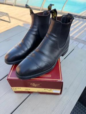 RM Williams Blaxland Boots – Svarta – Storlek 41,5 – Fint skick - Säljer ett par stilrena och klassiska RM Williams Blaxland boots i svart läder, storlek 41,5. Ett par exklusiva boots med tidlös design och fantastisk komfort som passar lika bra till jeans som till en mer uppklädd stil.  Skorna är i fint skick och väl omhändertagna. Gediget hantverk och hög kvalitet som RM Williams är kända för. Elastiska sidopaneler och robust sula gör dem både bekväma och hållbara för vardagsbruk.  • Märke: RM Williams • Modell: Blaxland • Färg: Svart • Storlek: 41,5 