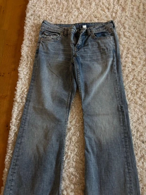 Ljusblå bootcut jeans - Ljusblå jeans med bootcut passform och klassiska fem fickor. Jeansen har en lätt tvättad look och är tillverkade i denim. Perfekt för dig som gillar en avslappnad och tidlös stil. 