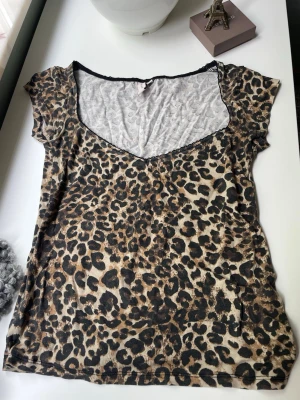 Leopardmönstrad topp från Nelly - Snygg leopardmönstrad topp från Nelly med v-ringning och korta ärmar. Tunn och mjuk kvalitet som känns skön mot huden. Perfekt för dig som vill sticka ut med ett djuriskt print och en trendig look.