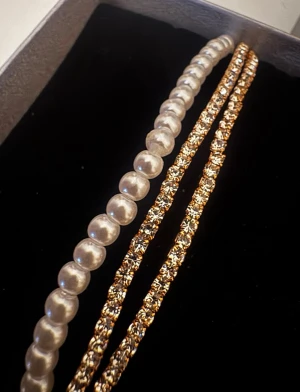 Pärlhalsband och guldfärgad kedja - Säljer ett klassiskt pärlhalsband med vita pärlor och en guldfärgad kedja från Guldfynd. Halsbanden levereras i originalask och passar perfekt för dig som gillar stilrena och tidlösa accessoarer.