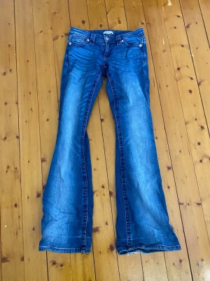 Blå bootcut jeans med utsvängda ben - Säljer ett par klassiska blå bootcut jeans från Gina tricot. Storlek xs lite slitna längst ner inget man tänker på