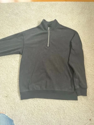 Svart half-zip hoodie från H&M - Mysig svart hoodie från H&M i relaxed fit med half-zip dragkedja framtill. Tillverkad i mjukt material med Thermolite-teknologi som håller dig varm. Perfekt för chill dagar och enkel att matcha med jeans eller mjukisbyxor.
