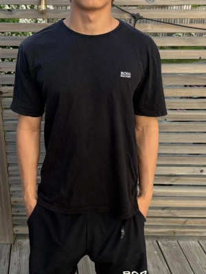 Svart t-shirt från BOSS - En stilren svart t-shirt från BOSS med liten vit logga på bröstet. Storlek M, modellen är 170cm och den är lite för stor. Skriv för frågor!