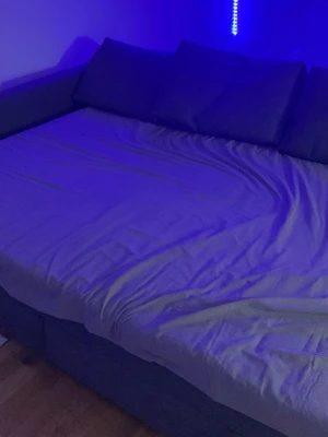 Grå bäddsoffa med hörn och kuddar - Säljer en stor grå bäddsoffa med hörn och tre matchande ryggkuddar. Soffan har en modern design och är klädd i tyg. Perfekt för dig som vill ha extra sovplats och en bekväm sittmöbel i vardagsrummet.