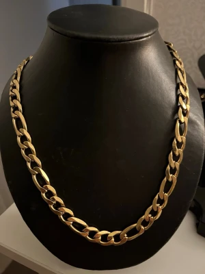 Guldfärgat kedjehalsband - Snyggt halsband i guldfärg med breda, platta länkar som ger en chunky och trendig look. Perfekt för att lyfta vilken outfit som helst med lite extra bling. Materialet ser ut som metall och halsbandet har en klassisk kedjedesign.