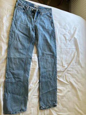 Ljusblå raka jeans från 157 - Säljer ett par ljusblå jeans från 157 med rak passform och klassisk femficksdesign. Jeansen har knappgylf och är tillverkade i denim med tydliga sömmar. Perfekta för en avslappnad och trendig look.
