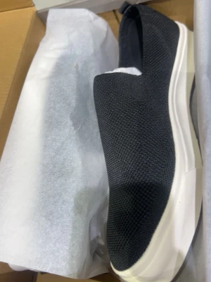 Svarta slip-on sneakers med vit sula- finns olika storlekar  - Snygga svarta slip-on sneakers med ovandel i mesh-tyg och tjock vit sula. Skorna har en minimalistisk design utan snörning och är lätta att ta på. Perfekta för dig som gillar enkel och stilren look.