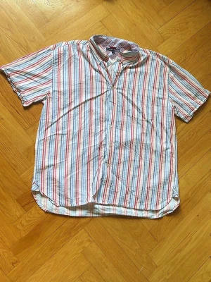 Randig kortärmad skjorta  - Kortärmad skjorta fr med vertikala ränder. Klassisk krage och knäppning framtill. Tillverkad i mjuk bomull, perfekt för varma dagar. Avslappnad passform och tidlös design som funkar till det mesta.