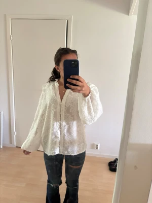 Vit spetsblus med knappar - Säljer en romantisk vit blus i spets med knäppning framtill och v-ringning. Blusen har långärmade, lite puffiga ärmar och ett luftigt fall. Perfekt för dig som gillar en feminin och trendig stil. Passar mig som har storlek xs fast den är M. 