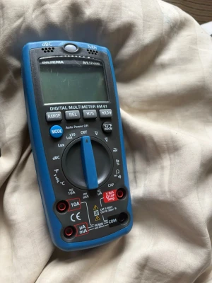 Digital multimeter Biltema EM 61 - Digital multimeter EM 61 från Biltema med blå och svart plastkropp. Har stor display, flera funktionsknappar och vred för olika mätlägen som spänning, ström och resistans. Perfekt för elektronikprojekt och felsökning.
