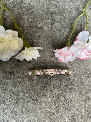 Söt hårklämma med pärlor och blommor - En hårklämma i metall dekorerad med små rosa blommor, pärlor och hjärtformade detaljer. Perfekt för att piffa till frisyren med en romantisk touch 🥰✨dessa hårspännens design är handgjorda och har lackats för bästa kvalitet. Vi är ett UF företag som säljer hårspännen. Spännena är enkla att fästa i frisyren.