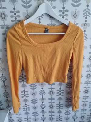 Gul croppad långärmad topp H&M - Trendig gul croppad topp från H&M med långa ärmar och ribbad struktur. Perfekt för att lyfta din outfit med en poppig färg och snygg passform. Rund halsringning och mjukt material som känns skönt mot huden.