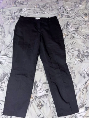 Svarta kostymbyxor raka ben - Stilrena svarta kostymbyxor med raka ben och klassisk passform. Perfekta till skjorta eller t-shirt för en clean look. Byxorna har diskreta fickor i sidorna och är tillverkade i ett mjukt material som känns bekvämt hela dagen.