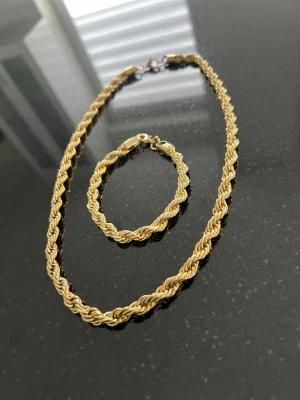 Cordell set - Säljer ett snyggt set med halsband och armband i guldfärg. Båda har en tvinnad kedjedesign som ger en lyxig känsla. Perfekt för att lyfta din outfit med lite extra bling. Lätta att matcha med andra smycken.