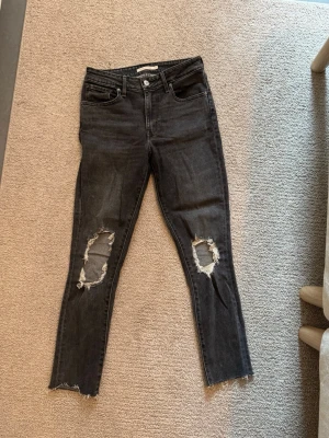Mörkgrå jeans - Mycket fina Levis jeans med hål för knäna. Storlek 27. Har passat mig som är ca 165 cm lång. Bra skick! High rise skinny är modellen. 