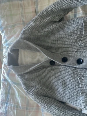 Grå stickad cardigan  - Mysig grå stickad kofta med stora svarta knappar och två framfickor. Koftan är perfekt nu inför våren och sommaren. Perfekt för lager på lager och har en klassisk, avslappnad look.