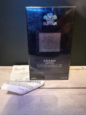 Creed Aventus Eau de Parfum 100ml - Creed Aventus Eau de Parfum är en exklusiv parfym i svart, lyxig förpackning med silverdetaljer och klassisk logotyp. Flaskan rymmer 100 ml och doften är känd för sina fruktiga och träiga noter. Perfekt för dig som vill ha en ikonisk och elegant signaturdoft.