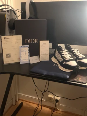 Svarta och vita D b25 sneakers - Snygga D sneakers i svart och vitt med klassiskt D-mönster på sidan. Skorna har en chunky sula, meshdetaljer och mockaliknande partier. Perfekta för dig som vill ha en exklusiv och trendig look. Levereras med originalkartong och dustbag.