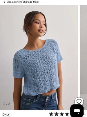 Ljusblå stickad cropped topp ONLY - Säljer en ljusblå stickad cropped topp från ONLY med korta ärmar och rund halsringning. Tröjan har ett luftigt hålmönster och vågig nederkant, perfekt för en trendig och avslappnad look.