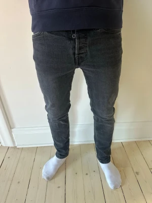 Jack and Jones jeans - Snygga svarta slim fit jeans med klassisk femficksdesign och normalhög midja. Jeansen har en smal passform hela vägen ner och är tillverkade i ett stretchigt denimtyg för extra komfort. Perfekta för en trendig och avslappnad stil.