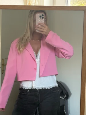 Kort rosa kavaj med enkel knapp - Trendig kort kavaj i starkt rosa med klassisk krage och en enkel knapp framtill. Rak passform och långa ärmar.