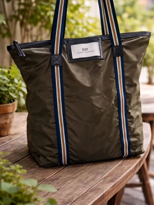 Olivgrön väska från DAY ET - Snygg olivgrön väska från DAY Birger et Mikkelsen. Väskan har långa axelband med blå, vita, röda och gröna ränder samt en svart dragkedja upptill. Tillverkad i slitstark nylon med en stilren logopatch framtill.