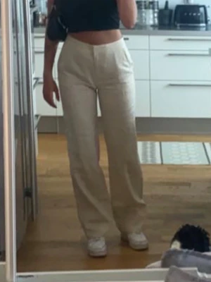 Beiga linnebyxor raka ben - Säljer ett par beiga linnebyxor med raka ben och hög midja. Byxorna har klassisk dragkedja och knapp framtill samt sidofickor. Perfekta för en avslappnad och stilren look. Materialet är luftigt linne som passar bra till sommaren.