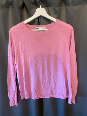 Rosa stickad tröja från Zara - En enkel, tun och snygg rosa stickad tröja från Zara. Tröjan har rund halsringning, långa ärmar och ribbade muddar vid ärmslut och nederkant. Perfekt till sommaren