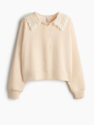Beige hoodie med spetskrage - Säljer an beige hoodie  med unik spetskrage och knytband framtill. Tröjan har en avslappnad passform, långa ärmar och ribbade muddar. Materialet är mjukt och bekvämt, perfekt för dig som vill ha en hoodie med lite extra detaljer. S