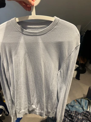 Ljusblå långärmad tröja från These glory days  - En enkel och stilren ljusblå långärmad tröja med rund halsringning och ribbade muddar. Tröjan har en mjuk och tunn struktur, perfekt för lager-på-lager och chill dagar.