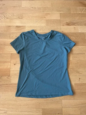Blå träningstopp från Energetics - Snygg blå t-shirt från Energetics i funktionsmaterialet DRYPLUS som håller dig torr under träningen. T-shirten har rund halsringning och korta ärmar, perfekt för gymmet eller löprundan.