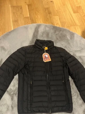 Svart dunjacka från Parajumpers - Säljer en svart dunjacka från Parajumpers med quiltad design och hög krage. Jackan har långärmade ärmar, dragkedja framtill och en gul detalj vid halsen. Perfekt för kalla dagar/blåsig och snygg att matcha med jeans eller sneakers. Jackan är köpt på blocket tidigare för 5000kr!