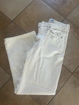 Vita raka jeans från 157 - Säljer ett par klassiska vita jeans från 157 med rak passform och fem fickor. Jeansen har normal midja och är tillverkade i ett mjukt bomullsmaterial. Perfekta för en clean och fräsch look året runt. Endast använda en gång. 