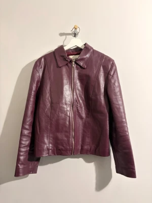 Vintage lila/vinröd  skinnjacka  - Vinröd skinnjacka med klassisk krage och rak passform. Perfekt för dig som vill ha en unik och trendig look. Köptes på en vintage affär i stockholm, skulle passa för både s/m