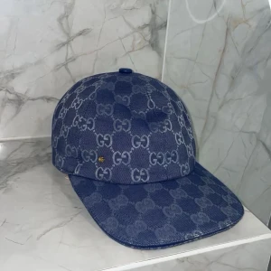 Blå keps - Säljer en blå keps med det klassiska mönstret över hela kepsen. Kepsen har böjd skärm och justerbar baksida. Perfekt för dig som vill ha en stilren accessoar med lyxig känsla.