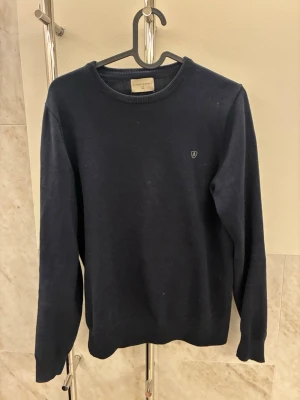 Mörkblå tröja från Morris - Klassisk mörkblå tröja från Álvaro moreno. Tröjan är stickad och är i okej skick. Det ända är att den har ett hål i armhålan men som dock inte syns vid användning och är lätt att fixa. Storleken är XS.