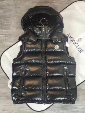 Svart dunväst från Moncler - Snygg svart dunväst från Moncler med glansig finish, huva och två dragkedjefickor framtill. Västen har Moncler-logga på bröstet och quiltad design. Perfekt för lager-på-lager och streetstyle.
