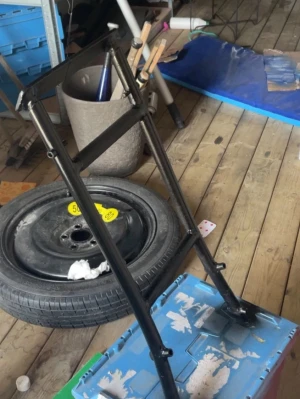 Svart metallram till pirra - Säljer en svart metallram till pirra eller transportkärra. Ramen är avlång med handtag upptill och plats för hjul nedtill. Perfekt för dig som vill bygga eller laga en egen pirra. Inga hjul eller platta medföljer.