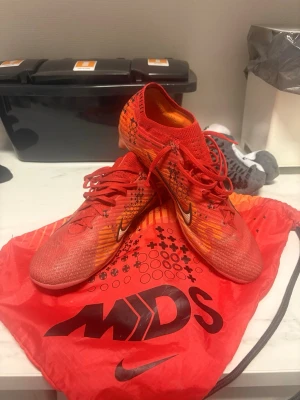 Nike Mercurial Dream Speed fotbollsskor - Säljer ett par Nike Mercurial Dream Speed fotbollsskor i rött och orange med svarta och vita detaljer. Inte använt skorna så mycket då jag varit skadad i 2 år. Påse o box skickar jag i. Hör av er om frågor👍