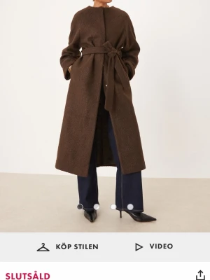 Asos Brun ullkappa med knytskärp - Helt ny, med prislapp. Stilren brun kappa i ullmix med figursydd passform och knytskärp i midjan. Kappan har diskreta fickor och en enkel, minimalistisk design utan synliga knappar. Perfekt för dig som gillar en klassisk och tidlös look. Köpt för 1279 på Asos storlek xs men passar även S.