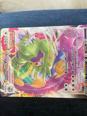 Tornadus VMAX Pokémonkort - Säljer ett färgglatt Tornadus VMAX Pokémonkort från Sword & Shield-serien. Kortet har holografisk yta och visar Tornadus i dynamisk pose med regnbågseffekter. Perfekt för samlare eller Pokémonfans som vill utöka sin kortsamling.