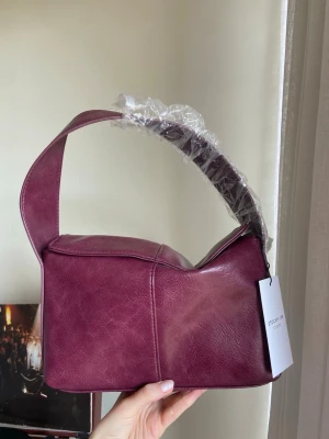 Vinröd axelväska från Stockh lm - Snygg vinröd handväska från Stockh lm, väldigt rymlig. Helt oanvänd och köpt för 599kr